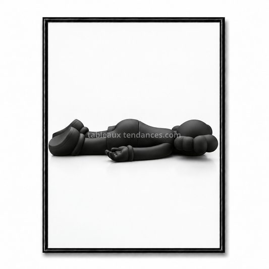 Tableau Kaws noir minimaliste avec personnage allongé horizontalement au sol sur fond blanc.